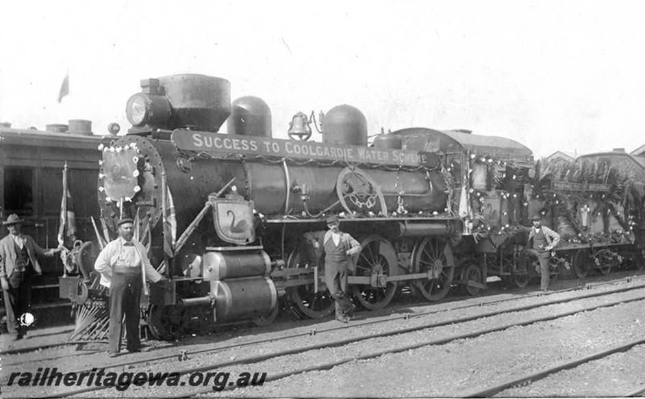 A group of men standing next to a train
Description automatically generated